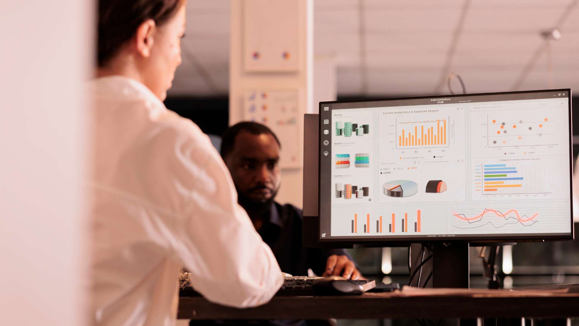 A woman looking at a computer monitor displaying charts, graphics and pie charts